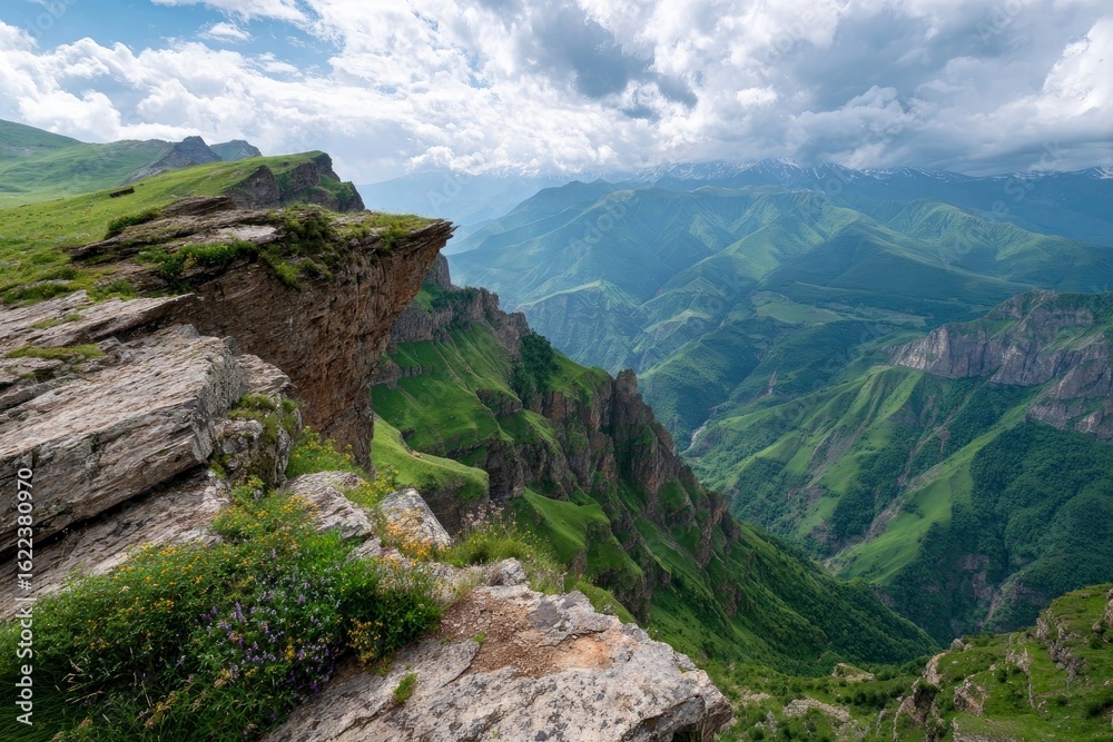 Obraz premium Verdant cliffs a valley and distant mountains under cloudy skies