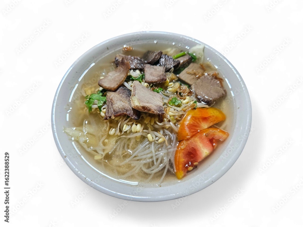 A bowl of traditional Indonesian beef noodle soup served with fresh vegetables and tomato slices on white background, perfect for culinary and food industry visuals A bowl of traditional Indonesian beef noodle soup served with fresh vegetables and tomato slices on white background, perfect for culinary and food industry visuals
