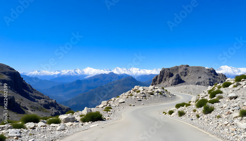 Winding mountain road with rocky terrain and snow.

