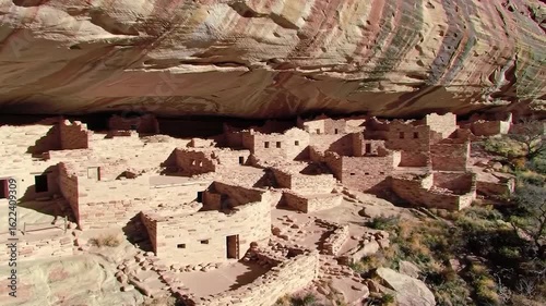 Ancient stone dwellings beneath a vast, curved rock overhang
