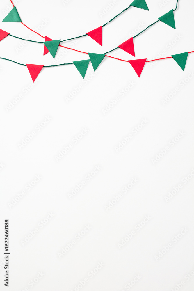 Fototapeta premium Minimalist festive bunting with red and green paper pennants on white. Simple yet vibrant composition, perfect for Mexican-themed backgrounds, holiday banners, or celebration materials.