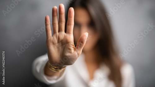 A woman holds up their hand to signal stop. Harassment at work. The setting appears dark, reflecting a serious atmosphere