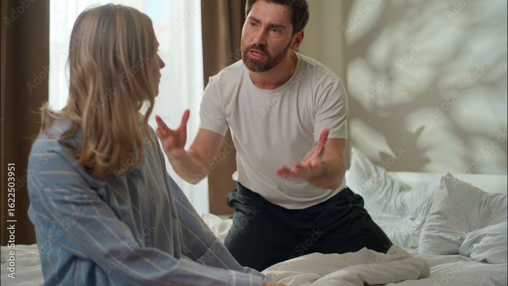 Fototapeta premium Upset Caucasian partners conflict arguing discussion in bedroom stressed couple dispute family frustrated wife talking pushing husband annoyed man shout woman disagreement relationship problem breakup