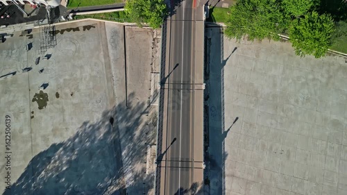 Aerial top-down dolly drone video beginning at Zielinski Bridge with views of Heroes’ Square, following the bridge into City Park along Kós Károly sétány in Budapest during calm morning light.