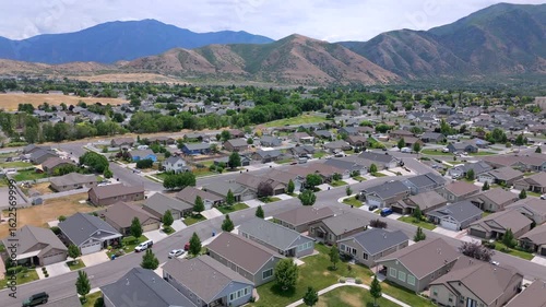 Stunning drone footage captures a serene Salt Lake City suburban community, showcasing an array of charming homes, spacious parks, and breathtaking mountain views. Utah, USA