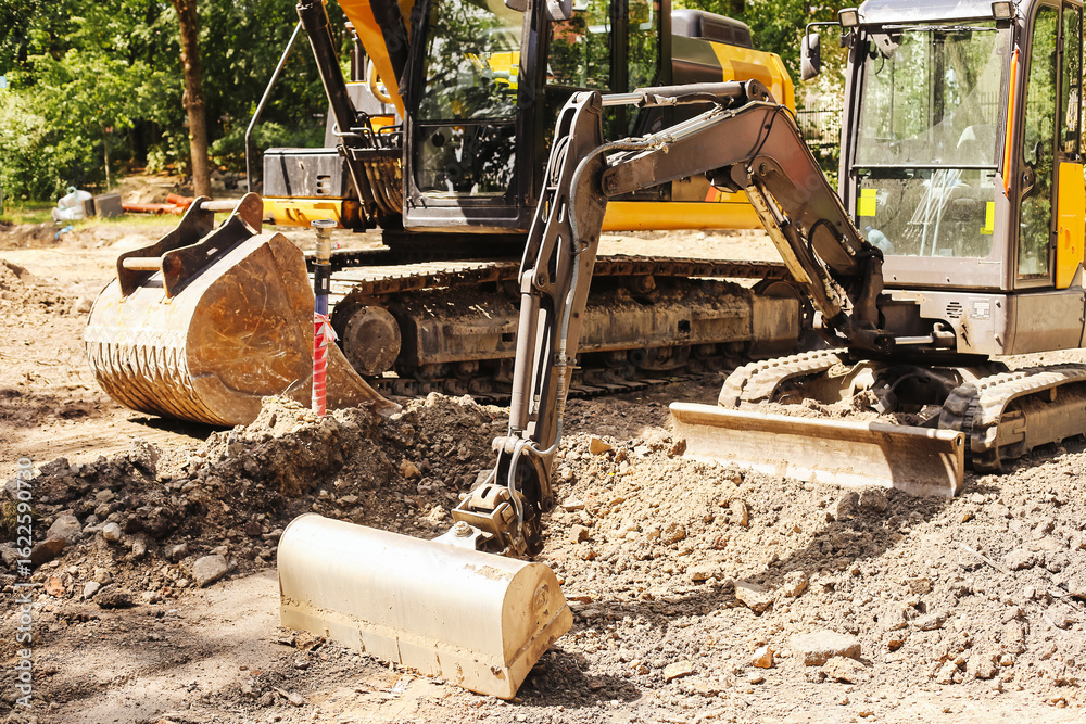 Fototapeta premium Excavator working on construction site. Heavy equipment digging soil. Earthmoving machine on sunny day. Bulldozer in background. Industrial development zone. Land preparation with digging tools.