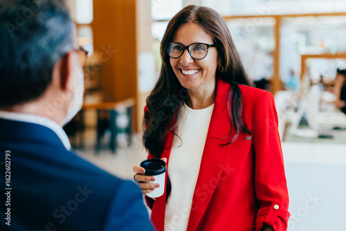 Fényképezés Professional woman smiling while conversing with colleague in business environme