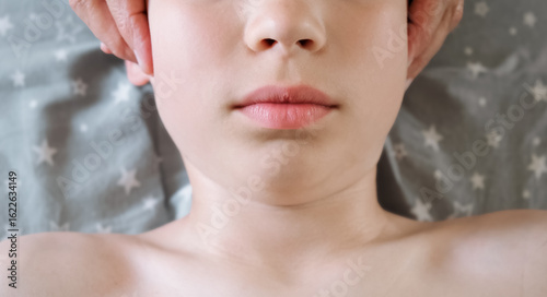 The masseur is massaging child's face. A session of therapeutic lymphatic drainage massage. Physiotherapy treatment. An osteopath removes tension from the jaw muscle and relieves pain in a joint.