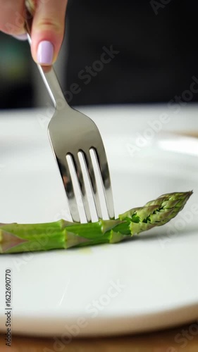 An extreme close-up overhead video of an anonymous hand lifting vibrant plant-based food with a silver fork from a minimalist white plate, bathed in soft natural light, shallow depth of field.