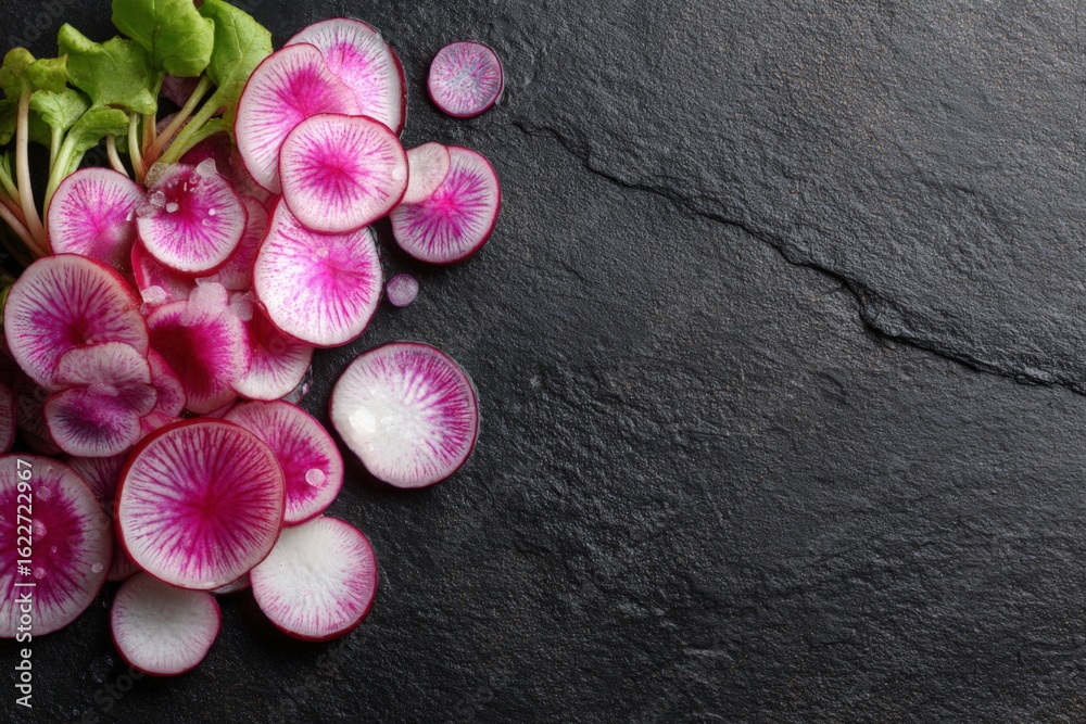 Obraz premium Vibrant pink radishes arranged on a dark stone surface showcasing fresh produce for healthy meals