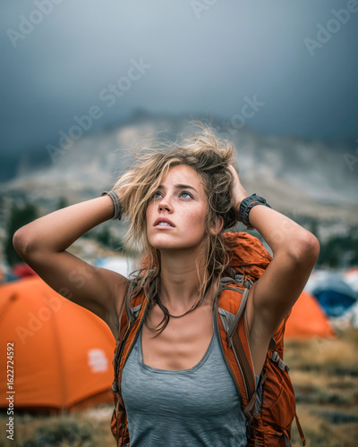 Young woman enjoys nature while camping in the mountains with a stormy sky in the background during late afternoon