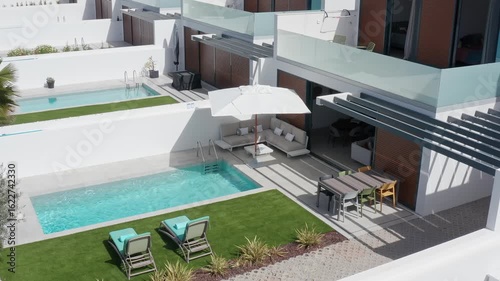 Several modern villas with private swimming pools, sun loungers, parasols, and outdoor furniture offer a luxurious and relaxing vacation experience