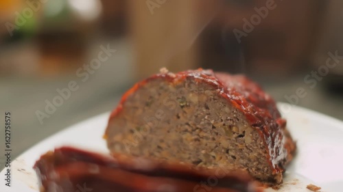 A wooden spatula lifts a juicy, mouth-watering piece of meatloaf from a plate. Close-up. High quality 4k footage