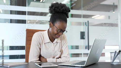 Sick african american businesswoman suffering from stomach pain working on laptop sitting at workplace in office. Upset black woman employee has gastritis, poisoning digestive problems or menstruation