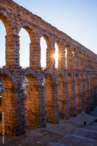 Segovia, Spain: The sun's rays shining through the Aqueduct of Segovia in the morning