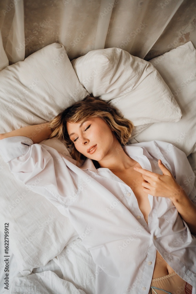 Obraz premium sexy woman in white shirt in bed. female attractiveness and sexuality. top view