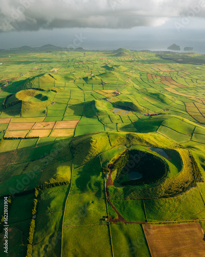 Aerial view of the vibrant patchwork fields and volcanic cones of Serra do Cume create a mesmerizing tapestry under a moody sky, Praia da VitÃ³ria, AÃ§ores, Portugal.