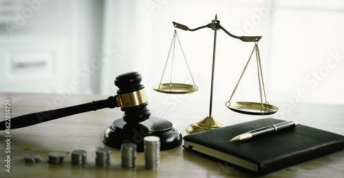 Photos A gavel rests beside stacked coins and a balance scale, symbolizing justice, legal decisions, financial regulation, law, economics, fairness, penalties, and courtroom-related monetary issues