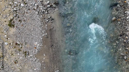 glacier creek, vertical flow framed rocky riverbed and sandbank, ice blue turquoise water, top down view, aerial, ease out movement