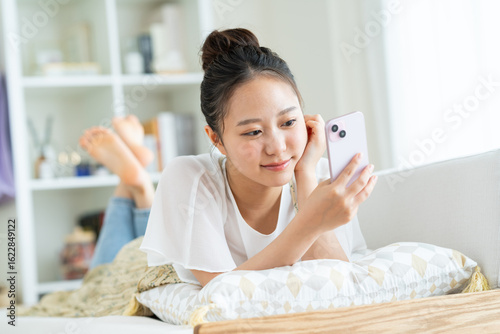 Obraz na płótnie リビングでスマホを見る女の子