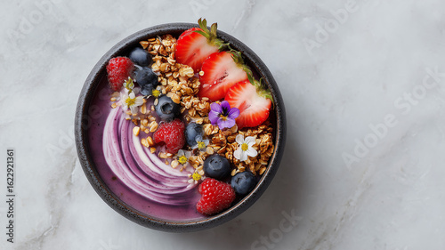 Aerial top-down view of a modern healthy breakfast bowl with acai, granola, and fresh berries on a light marble table, soft natural lighting, food photography style