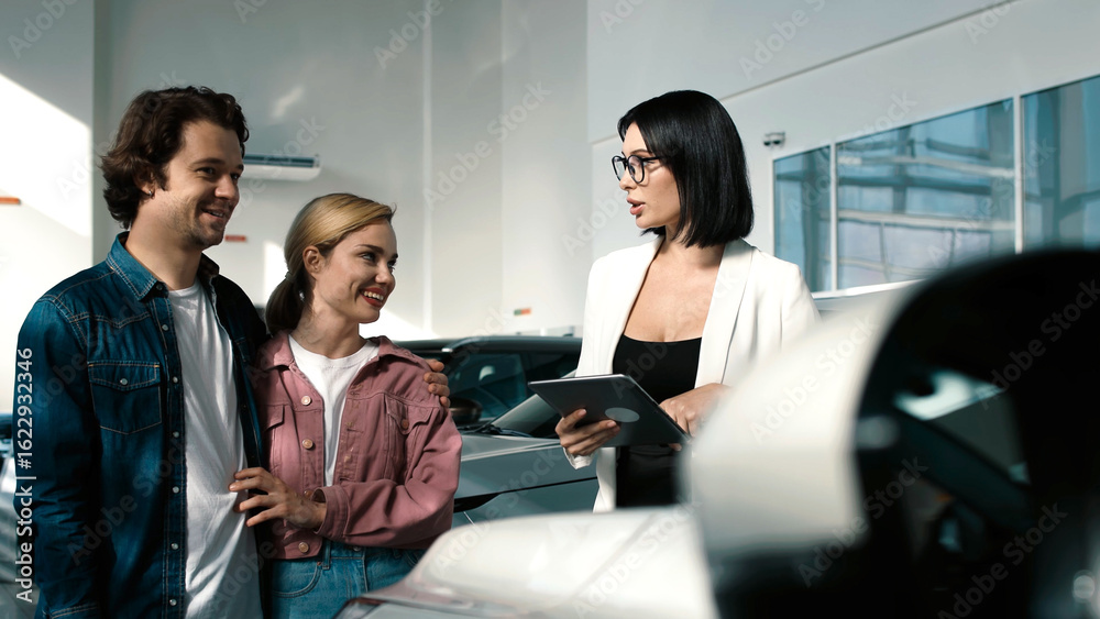 Obraz premium Couple engaging with a car dealer in a modern showroom, discussing vehicle options and features while exploring the latest models available