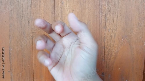 Portrait of a woman's hand knocking on the wooden door of a house.