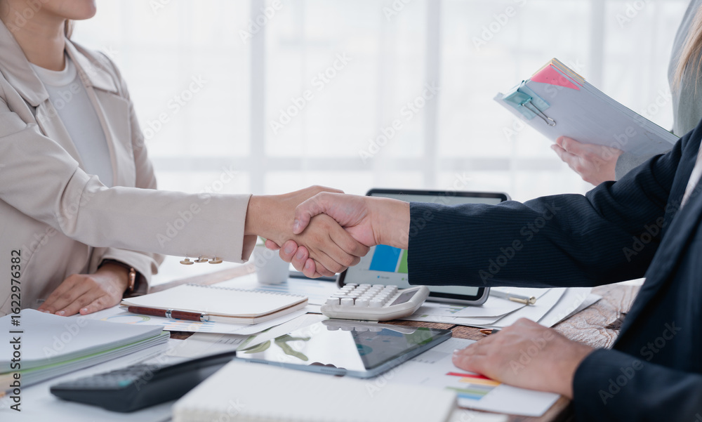 Business partners shaking hands after successful negotiations, reaching an agreement, finalizing a contract, or celebrating a collaborative achievement in a modern office setting Business partners shaking hands after successful negotiations, reaching an agreement, finalizing a contract, or celebrating a collaborative achievement in a modern office setting