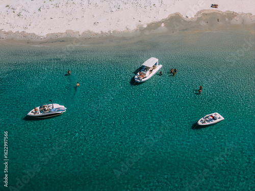 Crystal clear waters with boats and people enjoying a summer day at the beach