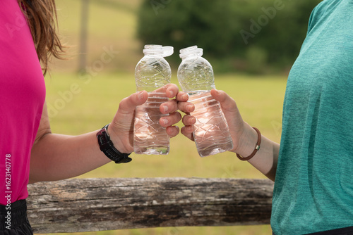 Women toasting with water after running in a park