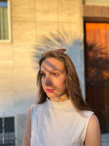 Young Female Model Portrait in Golden Hour Sunlight on her Face. Palm Tree Shadow in background