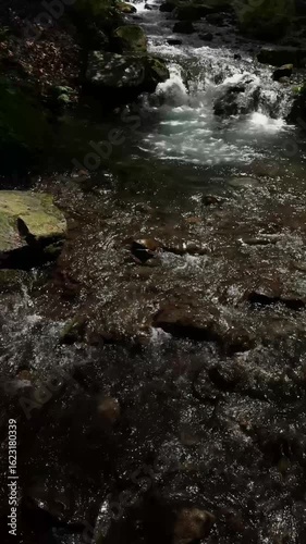 foamy stream of a mountain river over stones, waterfall