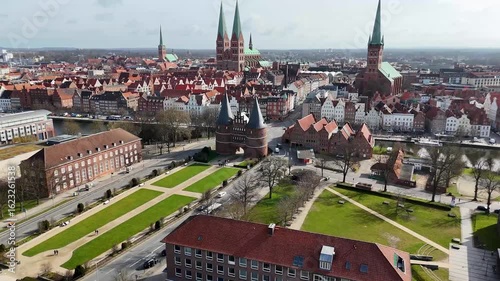 Aerial view of a historic European city of Lubeck, Germany with red-roofed buildings, a river, and a prominent cathedral.