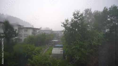 Looking through bedroom window seeing thunderstorm with heavy rain at Swiss city of Zürich. Movie shot August 1st, 2025, Zurich, Switzerland.
