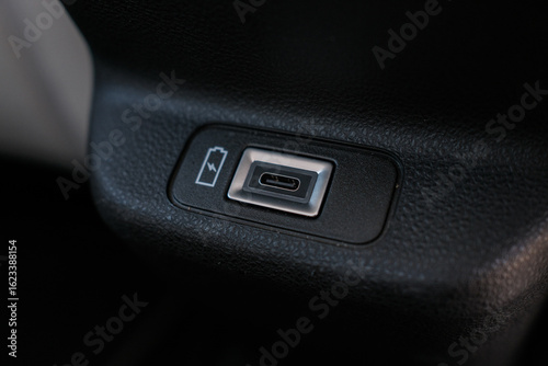 Close up of a universal serial bus (USB) charging port embedded in a textured dark colored surface indicating power accessibility