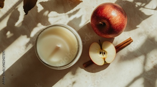 Minimalist apple-scented candle in frosted glass with sliced apple and cinnamon stick