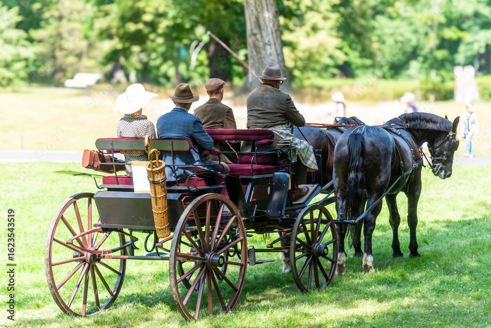 Fototapeta premium Horse-drawn carriage with coachman and passengers dressed in elegant interwar-era style outfits.