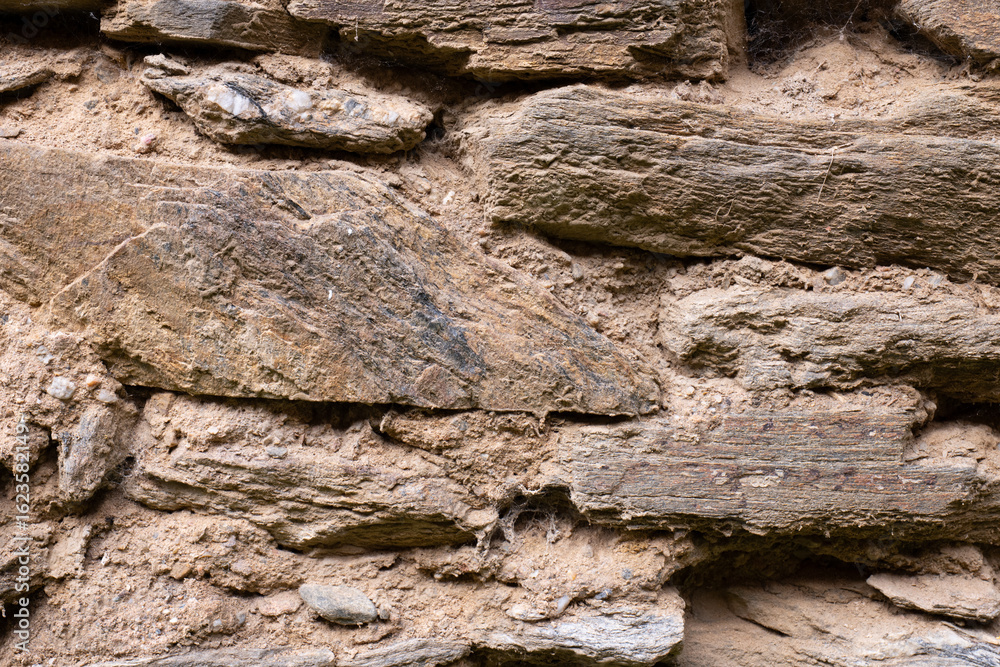 Fototapeta premium Close-up of dry stacked stone wall with earthy mortar 