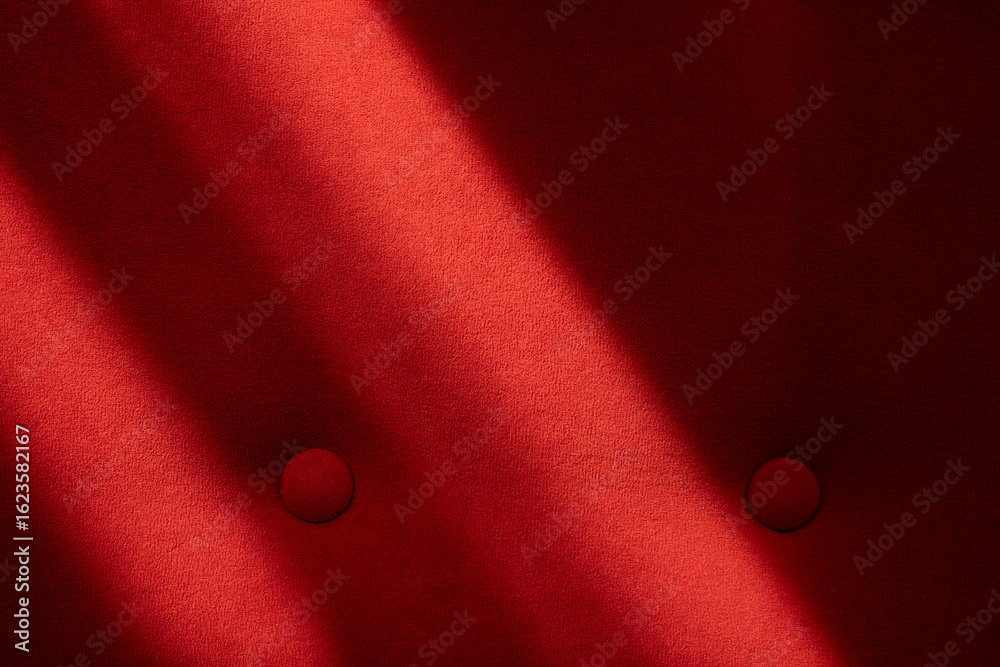 Red upholstered surface with sunlight and buttons
Red upholstered surface with sunlight and buttons