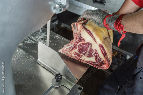 Φωτογραφία Butcher Cutting Dry Aged Ribeye Steak with Meat Saw on Stainless Table in Profes