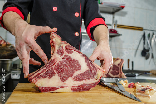 Fotografie Chef Displaying Dry Aged Ribeye Steak with Marbling on Wooden Cutting Board in K