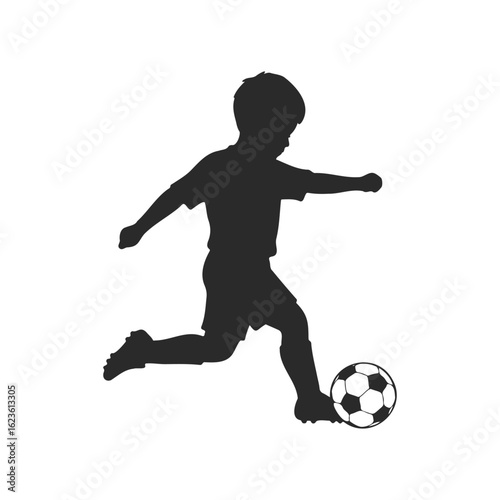 Silhouette of a young male child kicking a soccer ball
