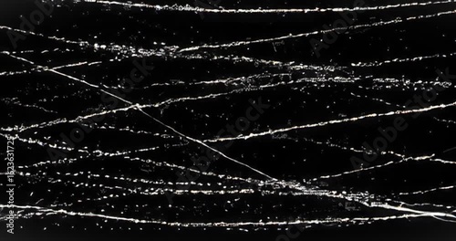 Animation imitates retro film damage with white scratches and dust particles over a black background.