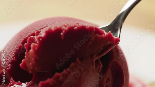 a spoon slowly scooping up a vibrant and delicious raspberry ice cream