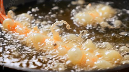 close-up of shrimp slowly frying in a pan with oil