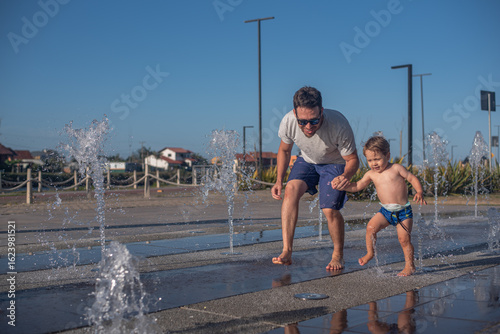 Father helping his son overcome fear of the splash pad