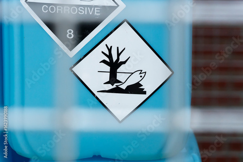 Photography Hazard sign with dead fish and tree on blue container