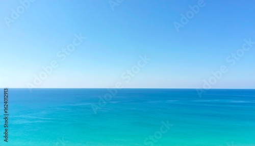 A serene, minimalist image of the ocean meeting the clear blue sky at the horizon, with subtle water texture.