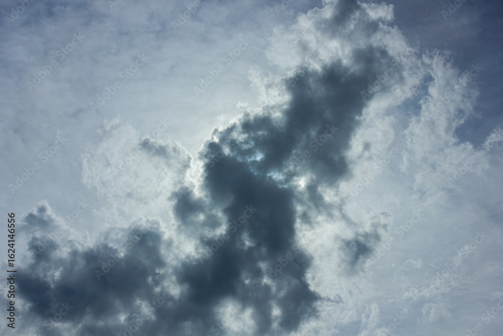 Obraz premium A dark grey storm cloud is backlit by the sun, creating a bright silver lining. Dramatic sky background