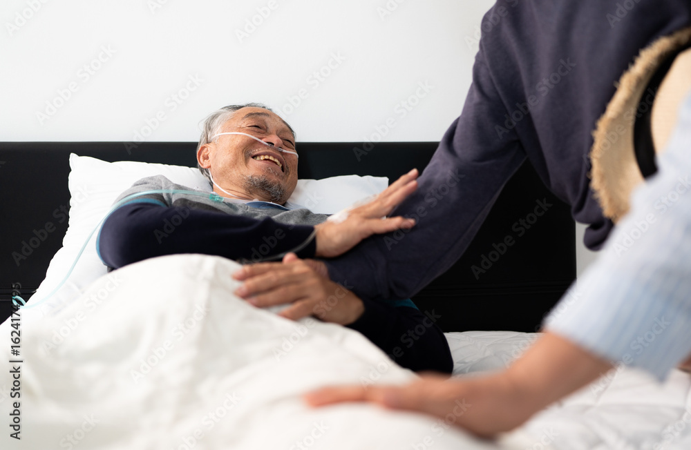 Obraz premium bedridden patient talking with friends, elderly hopeless senior man lying on bed with oxygen mask. home caregiver nurse visit retirement patient for health check up recovery process medical service